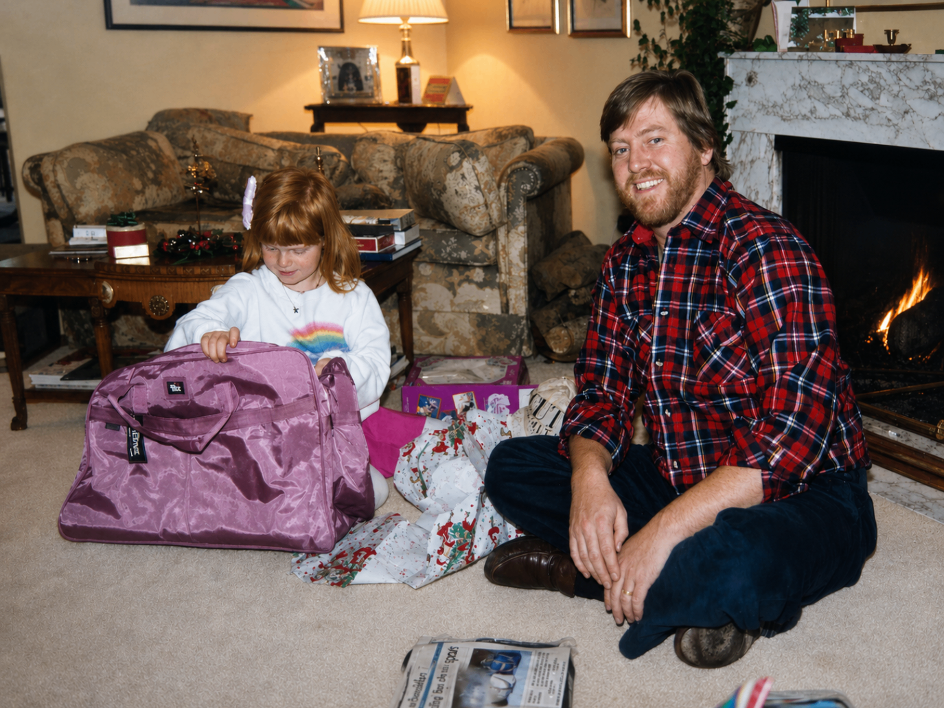 Dave sitting on the floor at Christmas with a young child opening gifts